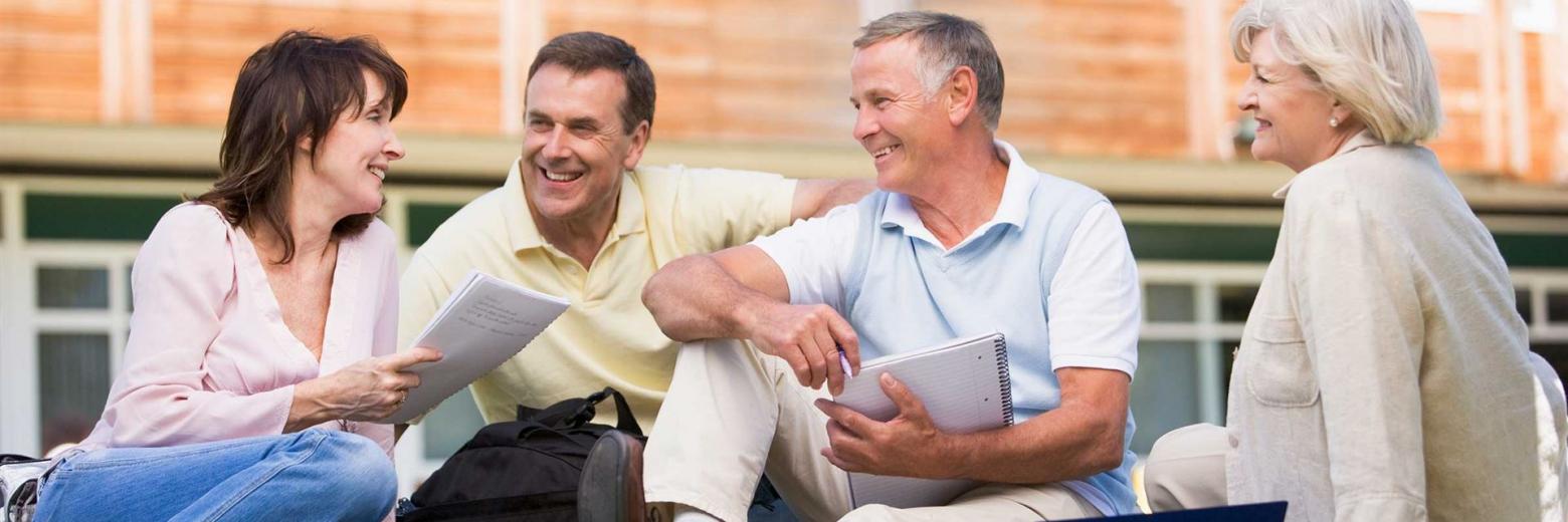 4 reife Erwachsene haben Spaß bei der Erwachsenenbildung mit Instructainment.